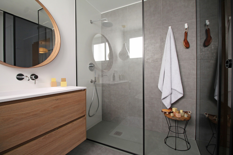 Idee per una stanza da bagno padronale minimalista di medie dimensioni con ante lisce, ante in legno scuro, doccia aperta, WC sospeso, piastrelle grigie, pareti bianche, lavabo integrato, pavimento grigio e top bianco