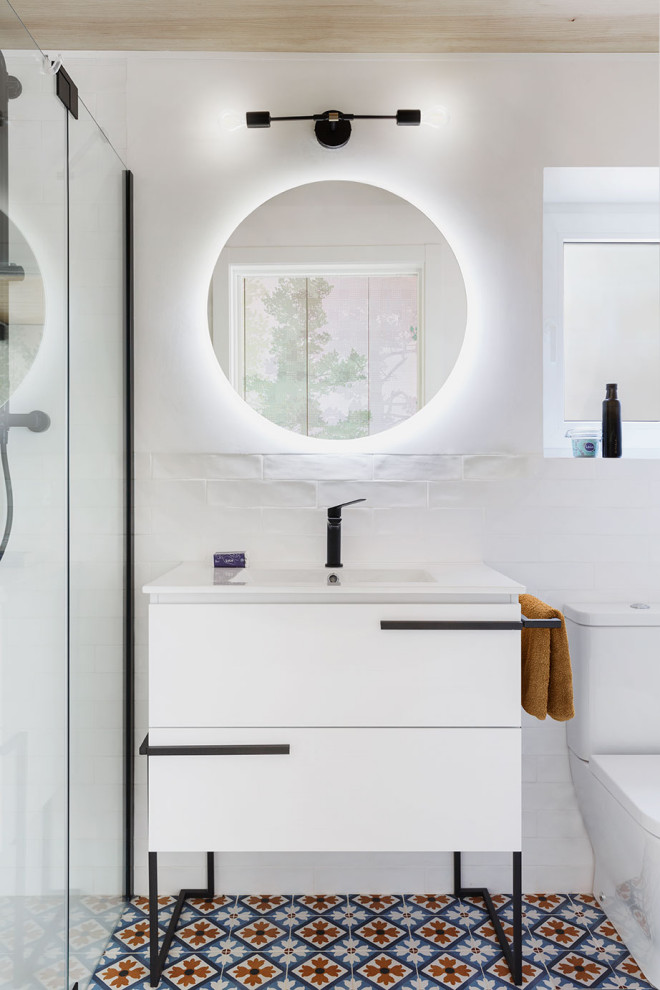 Inredning av ett minimalistiskt litet vit vitt badrum med dusch, med möbel-liknande, vita skåp, en kantlös dusch, en toalettstol med hel cisternkåpa, vit kakel, keramikplattor, vita väggar, klinkergolv i keramik, ett integrerad handfat, bänkskiva i kvarts, blått golv och dusch med gångjärnsdörr