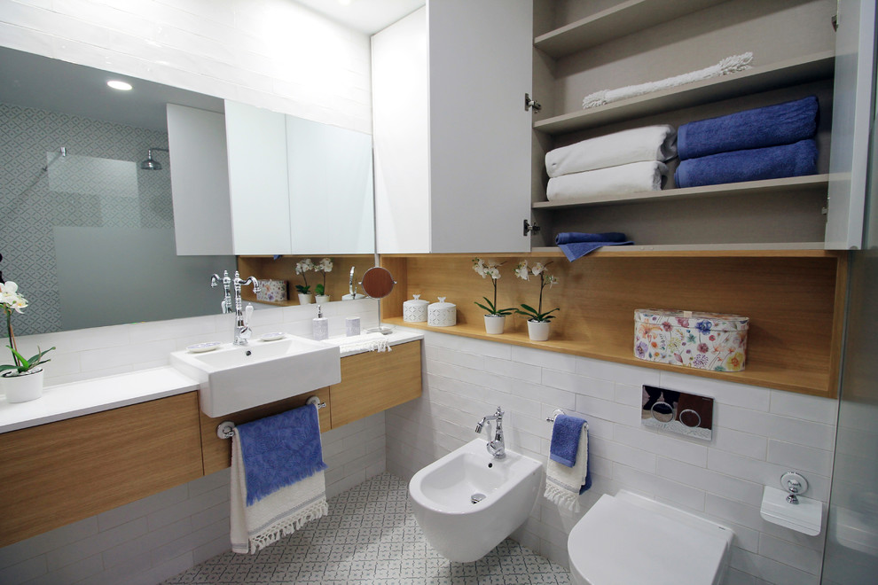 Exempel på ett mellanstort modernt en-suite badrum, med släta luckor, en vägghängd toalettstol, vita väggar, blått golv, skåp i mellenmörkt trä, blå kakel, mosaik, en hörndusch, ett nedsänkt handfat och mosaikgolv