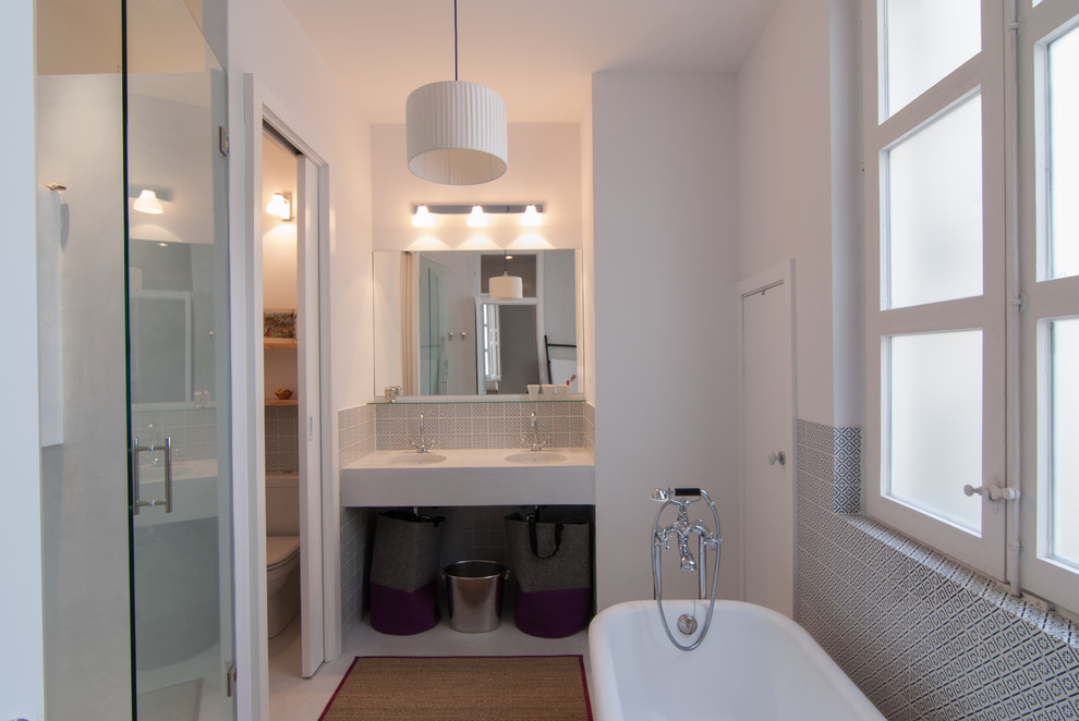Imagen de cuarto de baño principal escandinavo de tamaño medio con bañera exenta, combinación de ducha y bañera, paredes blancas, lavabo bajoencimera y microcemento