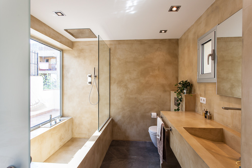 Modern inredning av ett mellanstort badrum med dusch, med ett badkar i en alkov, en dusch/badkar-kombination, en vägghängd toalettstol, beige väggar, betonggolv, ett avlångt handfat, med dusch som är öppen, öppna hyllor, beige skåp och grått golv