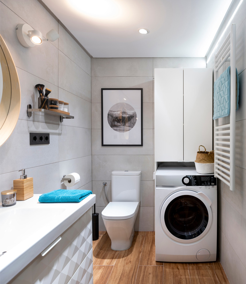 Inredning av ett minimalistiskt mellanstort vit vitt en-suite badrum, med luckor med upphöjd panel, vita skåp, en kantlös dusch, en toalettstol med hel cisternkåpa, grå kakel, keramikplattor, grå väggar, klinkergolv i keramik, ett avlångt handfat, bänkskiva i akrylsten, brunt golv och dusch med skjutdörr