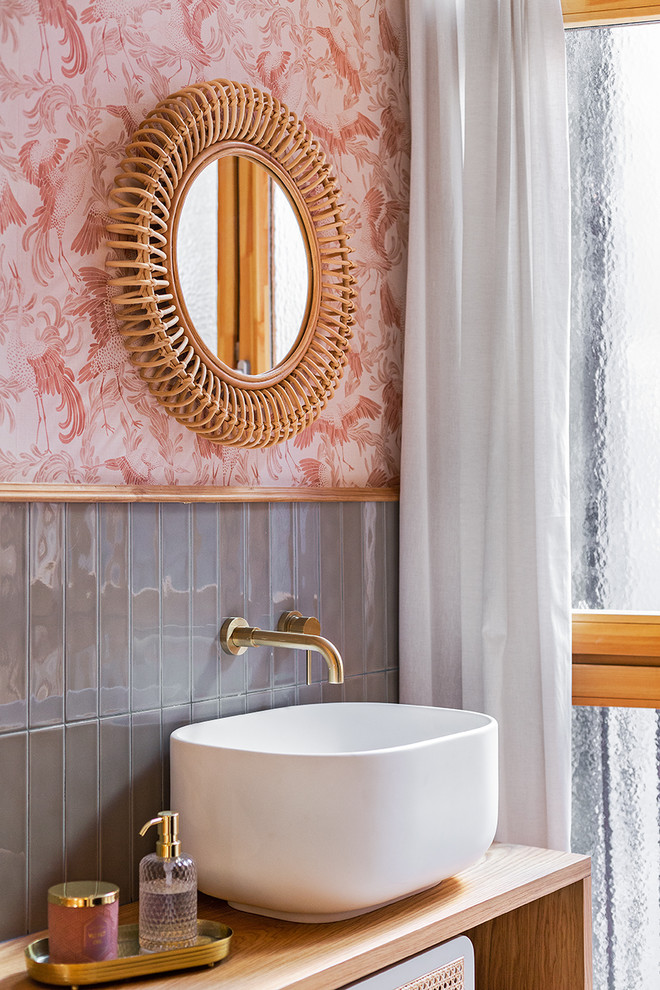 Klassisches Badezimmer mit offenen Schränken, grauen Fliesen, rosa Wandfarbe, Aufsatzwaschbecken, Waschtisch aus Holz und brauner Waschtischplatte in Barcelona