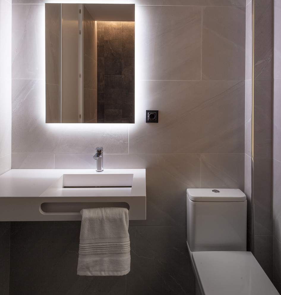 Foto de cuarto de baño actual con baldosas y/o azulejos grises, paredes grises, aseo y ducha, lavabo suspendido y encimeras blancas