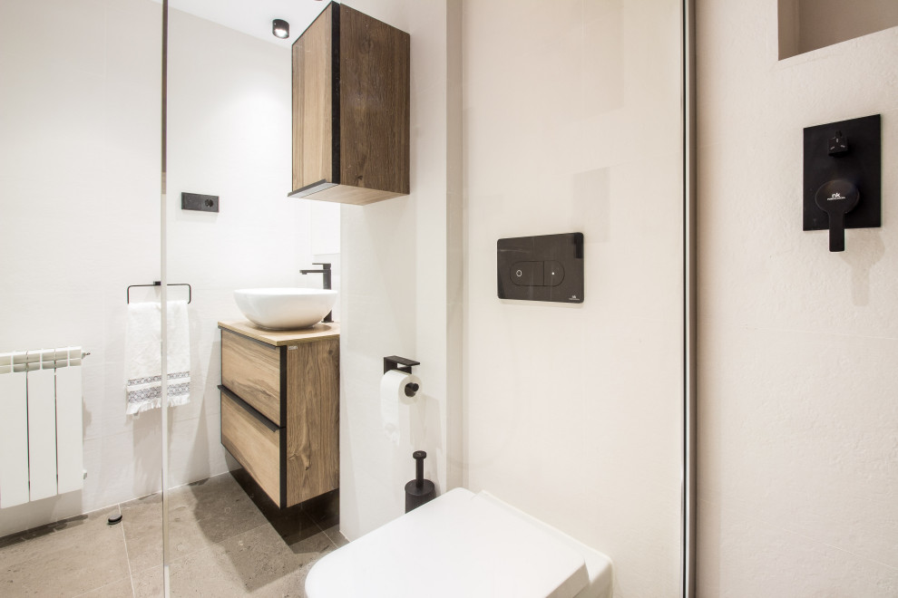 Photo of a small urban ensuite bathroom in Other with freestanding cabinets, white cabinets, a built-in shower, a wall mounted toilet, white tiles, ceramic tiles, white walls, cement flooring, wooden worktops, a hinged door, brown worktops, a single sink and a floating vanity unit.
