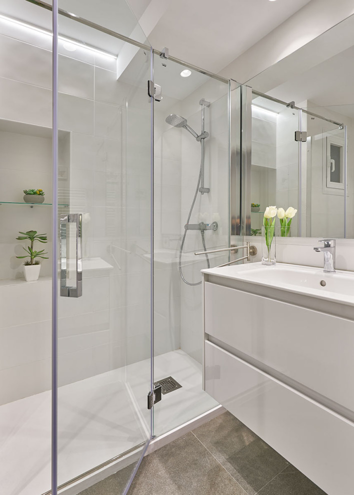 This is an example of a medium sized contemporary shower room bathroom in Bilbao with white worktops, flat-panel cabinets, white cabinets, an alcove shower, white tiles, porcelain tiles, white walls, porcelain flooring, an integrated sink, grey floors, a hinged door, a wall niche, a single sink and a floating vanity unit.