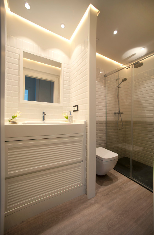 На фото: маленькая ванная комната в морском стиле с белыми фасадами, душем без бортиков, белой плиткой, керамической плиткой, белыми стенами, полом из ламината, душевой кабиной, настольной раковиной и столешницей из дерева для на участке и в саду