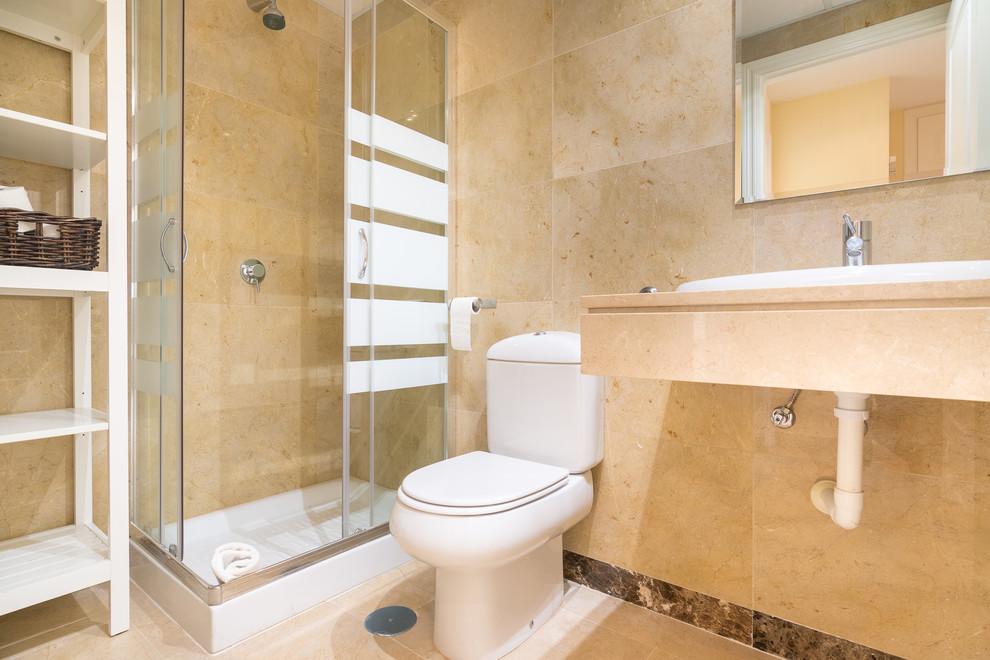Foto på ett stort maritimt en-suite badrum, med öppna hyllor, vita skåp, våtrum, ett urinoar, beige kakel, keramikplattor, beige väggar, klinkergolv i porslin, ett väggmonterat handfat, marmorbänkskiva, beiget golv och dusch med skjutdörr