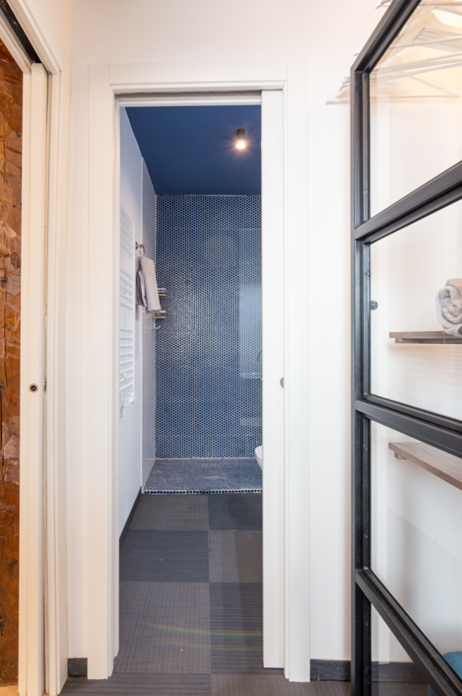 На фото: маленькая главная ванная комната в современном стиле с плоскими фасадами, белыми фасадами, душем без бортиков, писсуаром, белой плиткой, керамической плиткой, белыми стенами, полом из линолеума, монолитной раковиной, синим полом, душем с раздвижными дверями, тумбой под одну раковину и подвесной тумбой для на участке и в саду