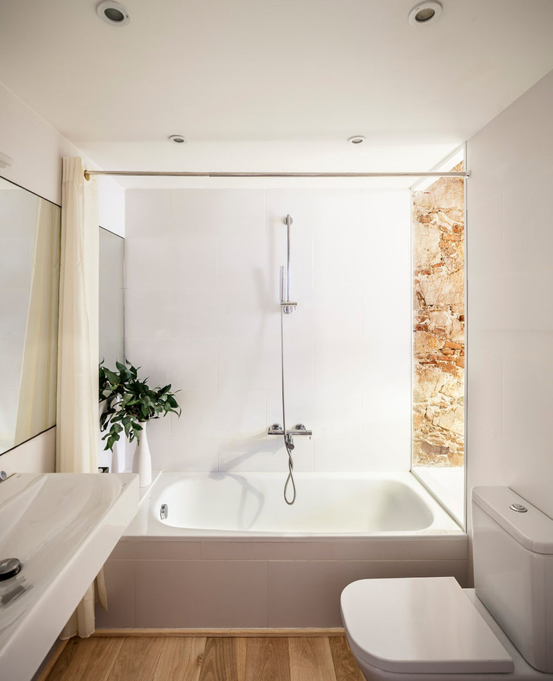 Idées déco pour une petite salle de bain principale contemporaine avec une baignoire en alcôve, un combiné douche/baignoire, WC séparés, un mur blanc, un sol en bois brun, un lavabo suspendu, un sol marron et une cabine de douche avec un rideau.