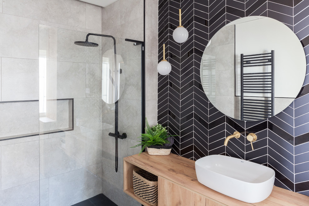 Idéer för att renovera ett stort minimalistiskt beige beige badrum med dusch, med keramikplattor, klinkergolv i keramik, ett fristående handfat, träbänkskiva, svart golv, släta luckor, skåp i ljust trä, en dusch i en alkov, svart kakel, blå kakel, flerfärgade väggar och med dusch som är öppen