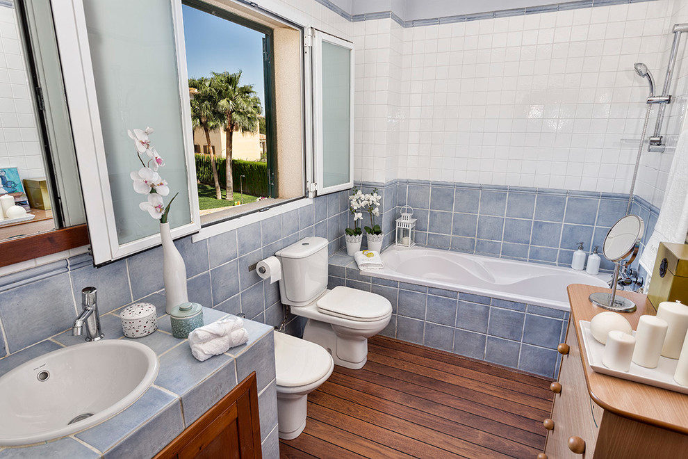 Réalisation d'une salle de bain principale chalet en bois brun de taille moyenne avec un placard en trompe-l'oeil, une baignoire en alcôve, un combiné douche/baignoire, WC séparés, des carreaux de céramique, un mur multicolore, un sol en bois brun, un lavabo encastré et un plan de toilette en carrelage.