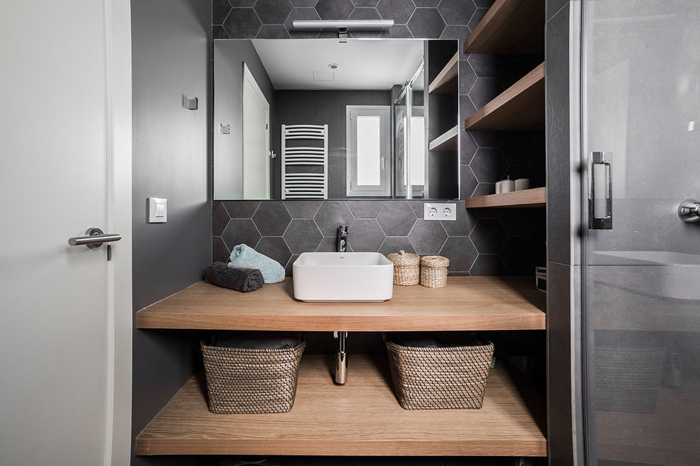 Idéer för att renovera ett mellanstort minimalistiskt en-suite badrum, med öppna hyllor, skåp i ljust trä, en kantlös dusch, en vägghängd toalettstol, grå kakel, keramikplattor, grå väggar, klinkergolv i porslin, ett fristående handfat, träbänkskiva, grått golv och dusch med skjutdörr