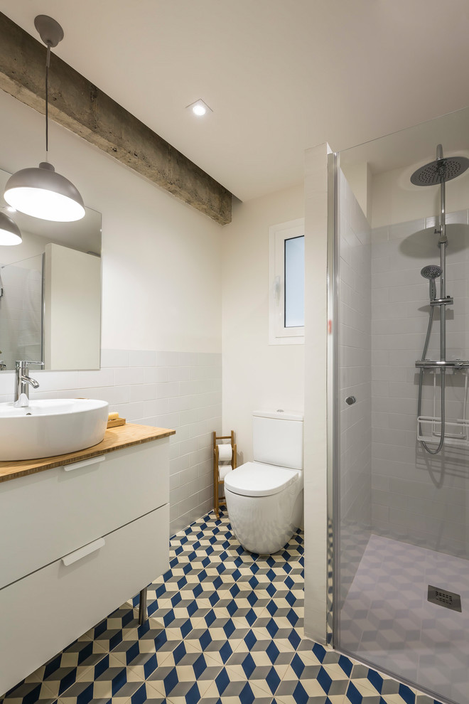 Пример оригинального дизайна: главная ванная комната среднего размера в современном стиле с белыми фасадами, душем в нише, унитазом-моноблоком, белой плиткой, плиткой кабанчик, белыми стенами, полом из мозаичной плитки, настольной раковиной, столешницей из дерева, разноцветным полом, душем с распашными дверями и плоскими фасадами