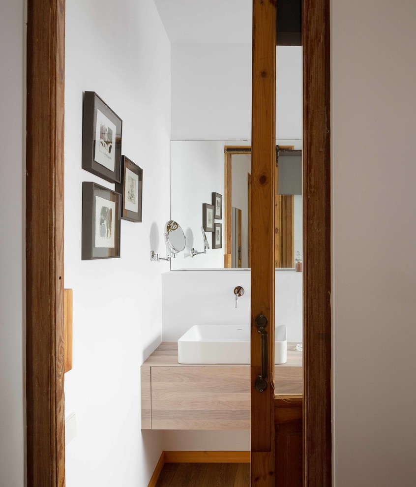 Idée de décoration pour une salle de bain principale urbaine en bois clair de taille moyenne avec un placard en trompe-l'oeil, une douche d'angle, WC suspendus, un mur blanc, un sol en bois brun, une vasque, un plan de toilette en bois et une cabine de douche à porte coulissante.