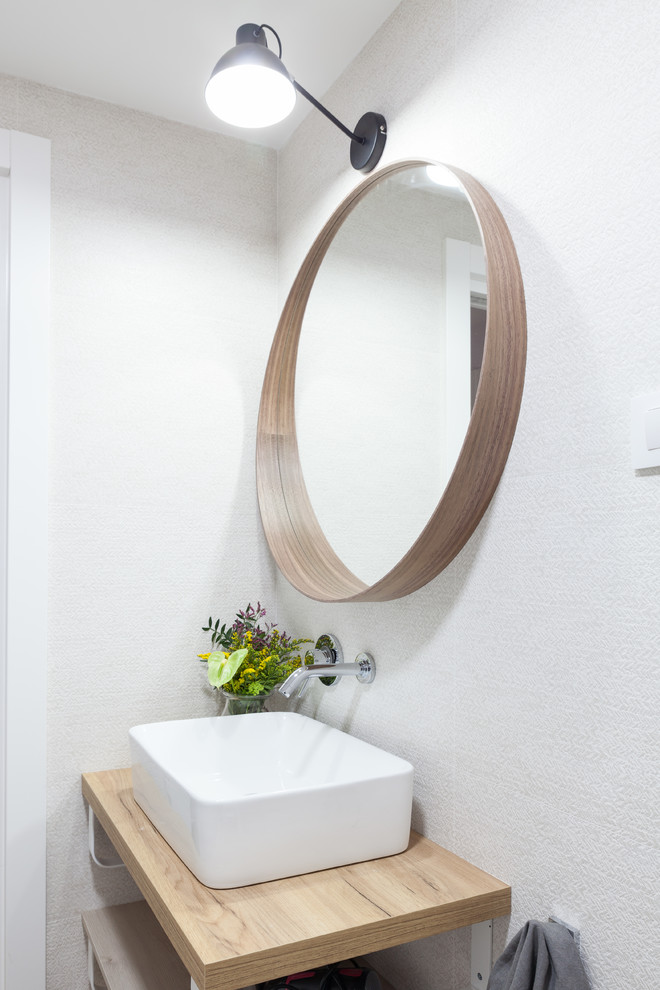 Foto di una piccola stanza da bagno padronale scandinava con nessun'anta, ante marroni, vasca ad angolo, vasca/doccia, WC sospeso, piastrelle beige, piastrelle in ceramica, pareti bianche, pavimento in laminato, lavabo a bacinella, top in legno, pavimento marrone, doccia aperta e top marrone