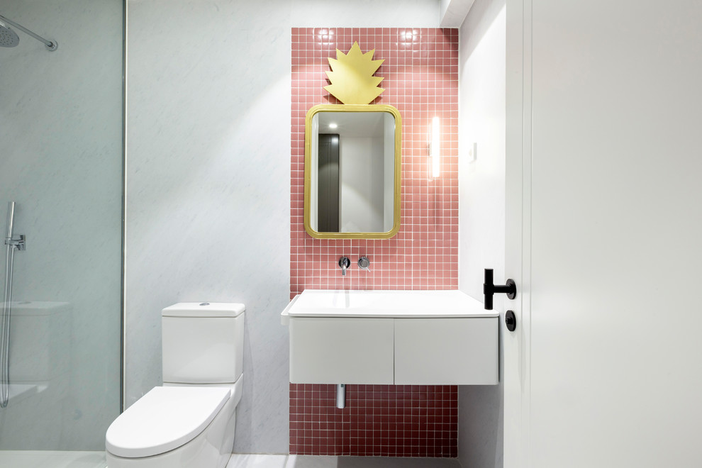 Modernes Duschbad mit flächenbündigen Schrankfronten, weißen Schränken, Wandtoilette mit Spülkasten, rosa Fliesen, Mosaikfliesen, integriertem Waschbecken und weißer Waschtischplatte in Sonstige