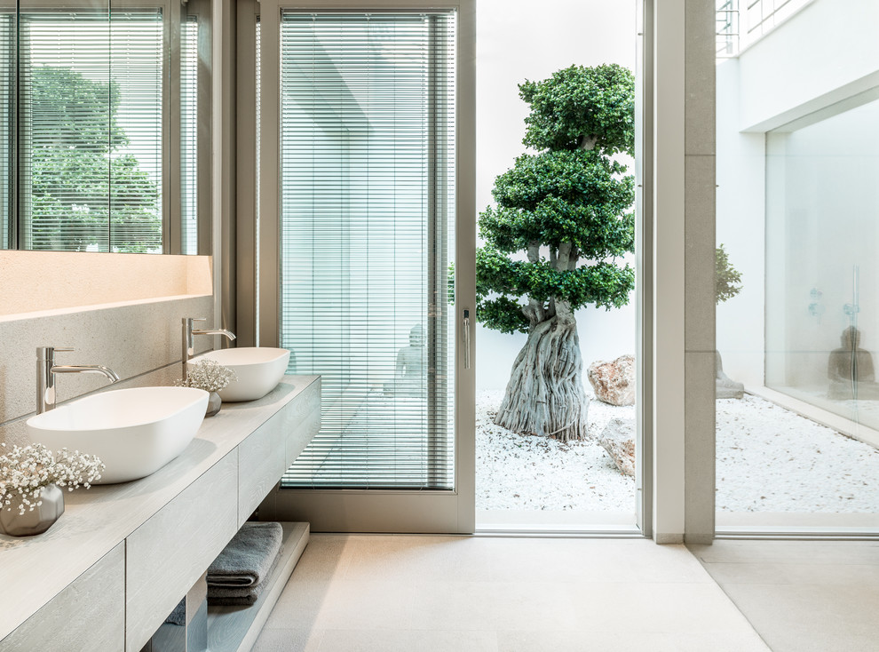 Inspiration pour une salle de bain principale marine en bois clair avec un placard à porte plane, une vasque, un plan de toilette en bois et un sol beige.