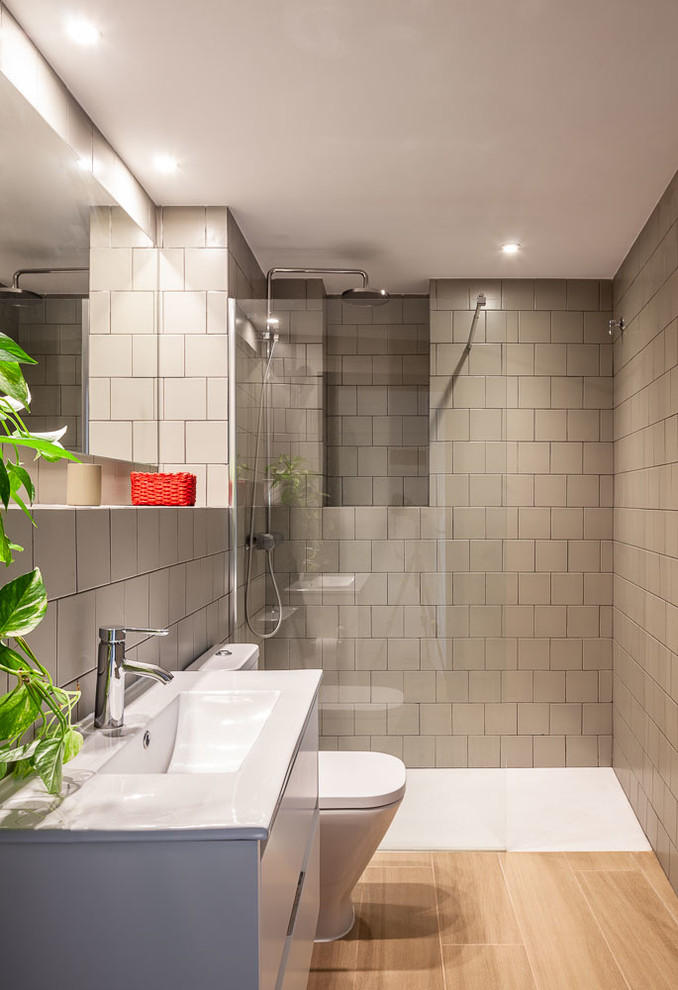 Bild på ett mellanstort funkis vit vitt badrum med dusch, med vita skåp, en kantlös dusch, keramikplattor, klinkergolv i porslin, släta luckor, grå kakel, ett integrerad handfat, beiget golv och med dusch som är öppen