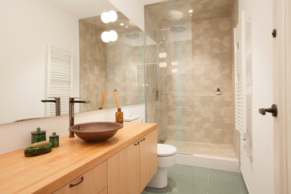 Modern inredning av ett litet brun brunt badrum med dusch, med släta luckor, skåp i mellenmörkt trä, en dusch i en alkov, vita väggar, ett fristående handfat, träbänkskiva, grönt golv, beige kakel och med dusch som är öppen