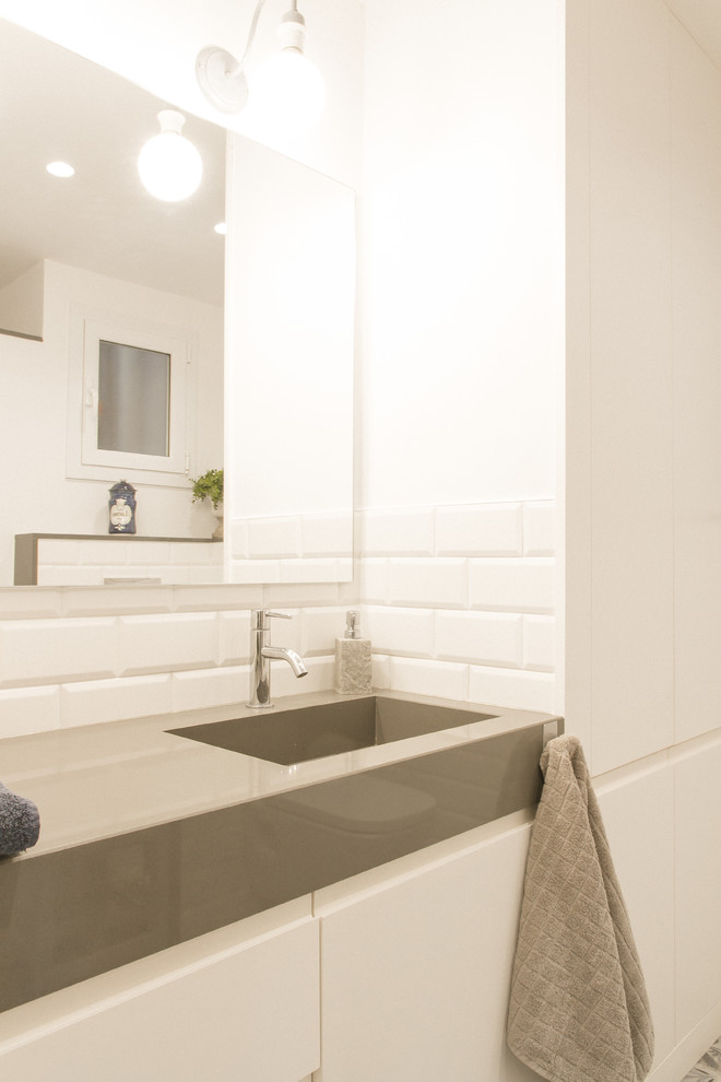Пример оригинального дизайна: главная ванная комната среднего размера в стиле лофт с плоскими фасадами, белыми фасадами, душем без бортиков, белой плиткой, керамической плиткой, полом из керамогранита, монолитной раковиной, столешницей из искусственного кварца и серой столешницей