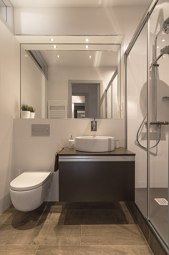 Cette photo montre une salle de bain industrielle avec un carrelage gris, des carreaux de porcelaine, un mur blanc, un sol en carrelage de porcelaine, une vasque et WC suspendus.