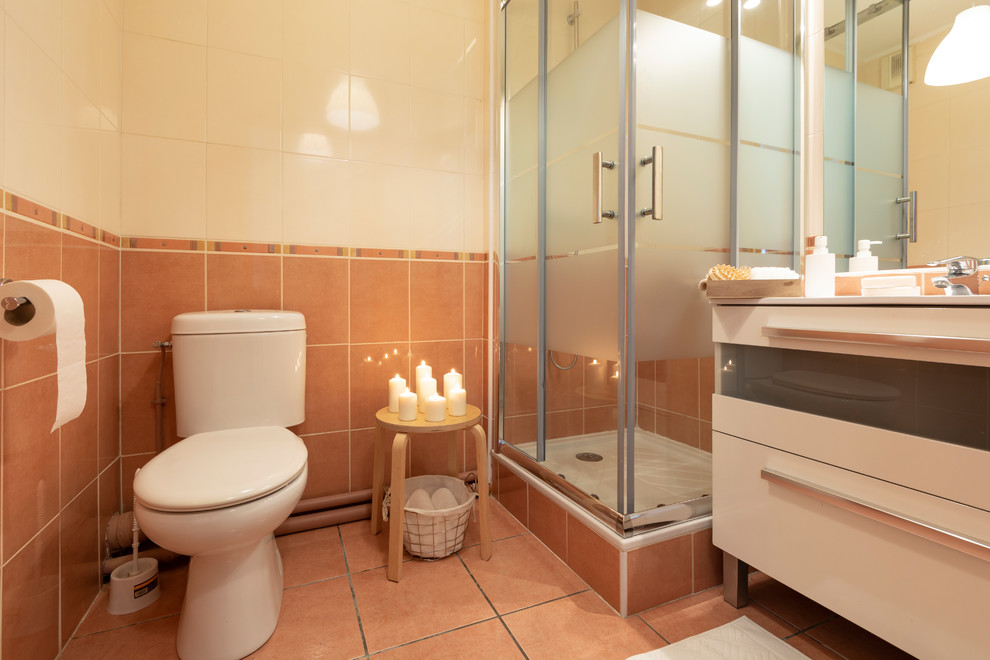 Источник вдохновения для домашнего уюта: маленькая ванная комната в современном стиле с фасадами с декоративным кантом, белыми фасадами, угловым душем, раздельным унитазом, оранжевой плиткой, керамической плиткой, оранжевыми стенами, полом из терракотовой плитки, душевой кабиной, настольной раковиной, столешницей из искусственного камня, оранжевым полом, душем с раздвижными дверями и белой столешницей для на участке и в саду