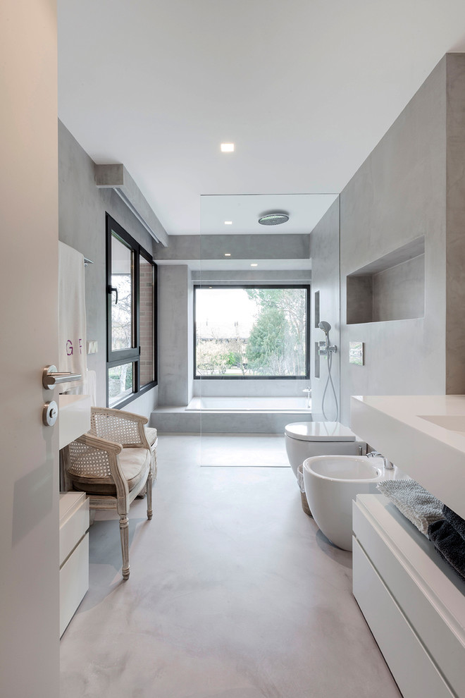 На фото: большая главная ванная комната в стиле модернизм с плоскими фасадами, белыми фасадами, душем без бортиков, биде, серыми стенами, бетонным полом, серым полом и белой столешницей с