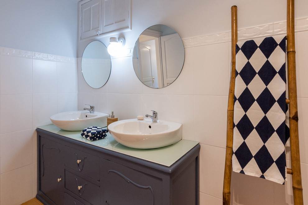 Aménagement d'une salle de bain montagne avec des portes de placard bleues, un carrelage blanc, un sol en carrelage de céramique, un plan de toilette en verre et un sol orange.