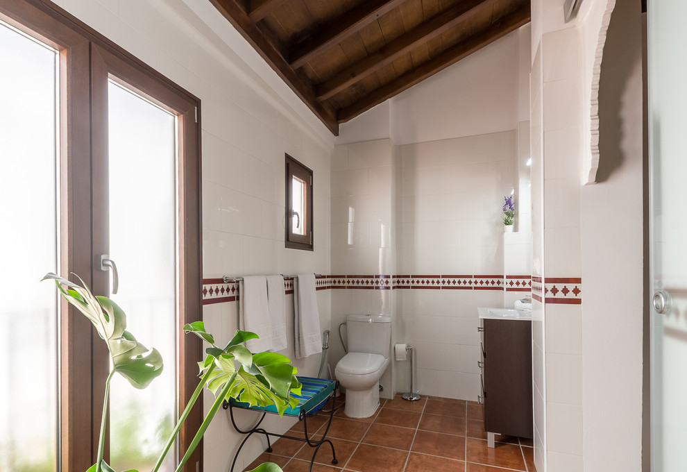 Ejemplo de cuarto de baño principal clásico renovado pequeño con armarios tipo mueble, puertas de armario marrones, ducha a ras de suelo, sanitario de una pieza, baldosas y/o azulejos blancos, baldosas y/o azulejos de cerámica, paredes blancas, suelo de baldosas de terracota, lavabo sobreencimera, suelo marrón y ducha abierta