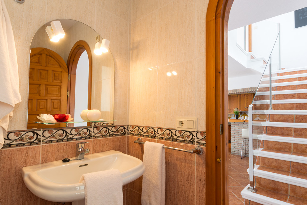 他の地域にある高級な小さな地中海スタイルのおしゃれなバスルーム (浴槽なし) (コーナー設置型シャワー、一体型トイレ	、ピンクのタイル、セラミックタイル、ピンクの壁、セラミックタイルの床、ペデスタルシンク、ベージュの床、引戸のシャワー) の写真