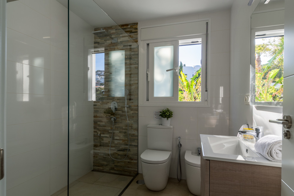 Photo of a small mediterranean shower room bathroom in Other with flat-panel cabinets, brown cabinets, a built-in shower, a one-piece toilet, white tiles, ceramic tiles, white walls, ceramic flooring, a built-in sink, marble worktops, beige floors and an open shower.