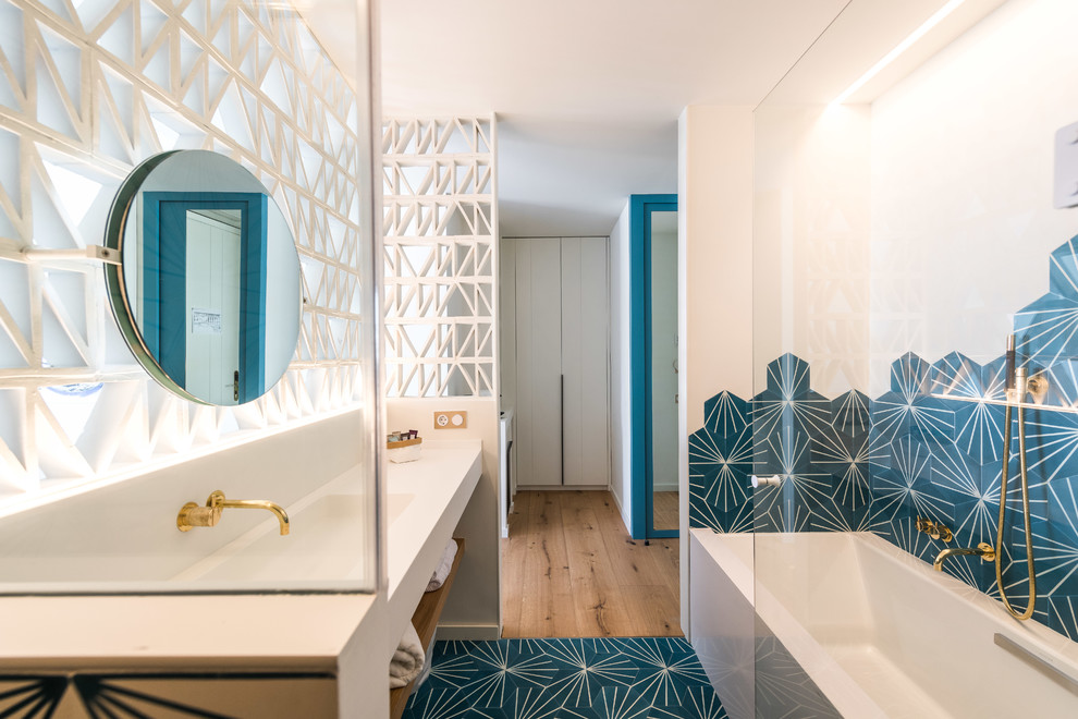 Inspiration pour une salle de bain design avec un placard sans porte, une baignoire posée, un carrelage bleu, un carrelage blanc, un lavabo intégré, un sol bleu, un plan de toilette blanc, un combiné douche/baignoire et un mur blanc.