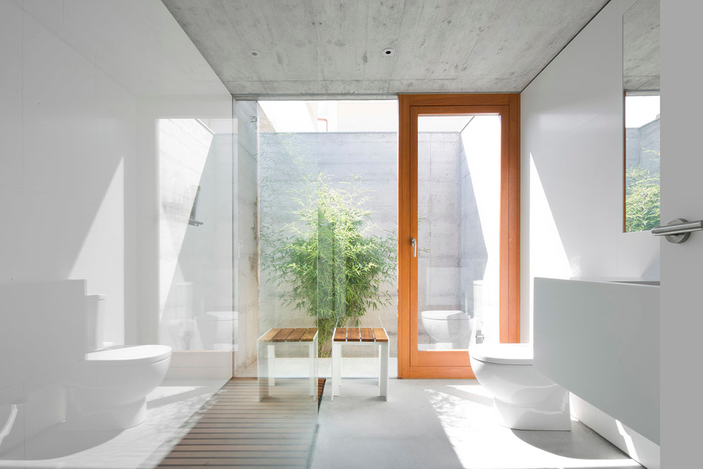 Foto di una stanza da bagno con doccia minimal di medie dimensioni con WC monopezzo, pareti bianche, doccia a filo pavimento e lavabo integrato