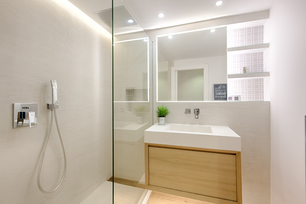 Foto de cuarto de baño minimalista pequeño con armarios con paneles lisos, puertas de armario de madera clara, ducha empotrada, paredes blancas, aseo y ducha y lavabo integrado