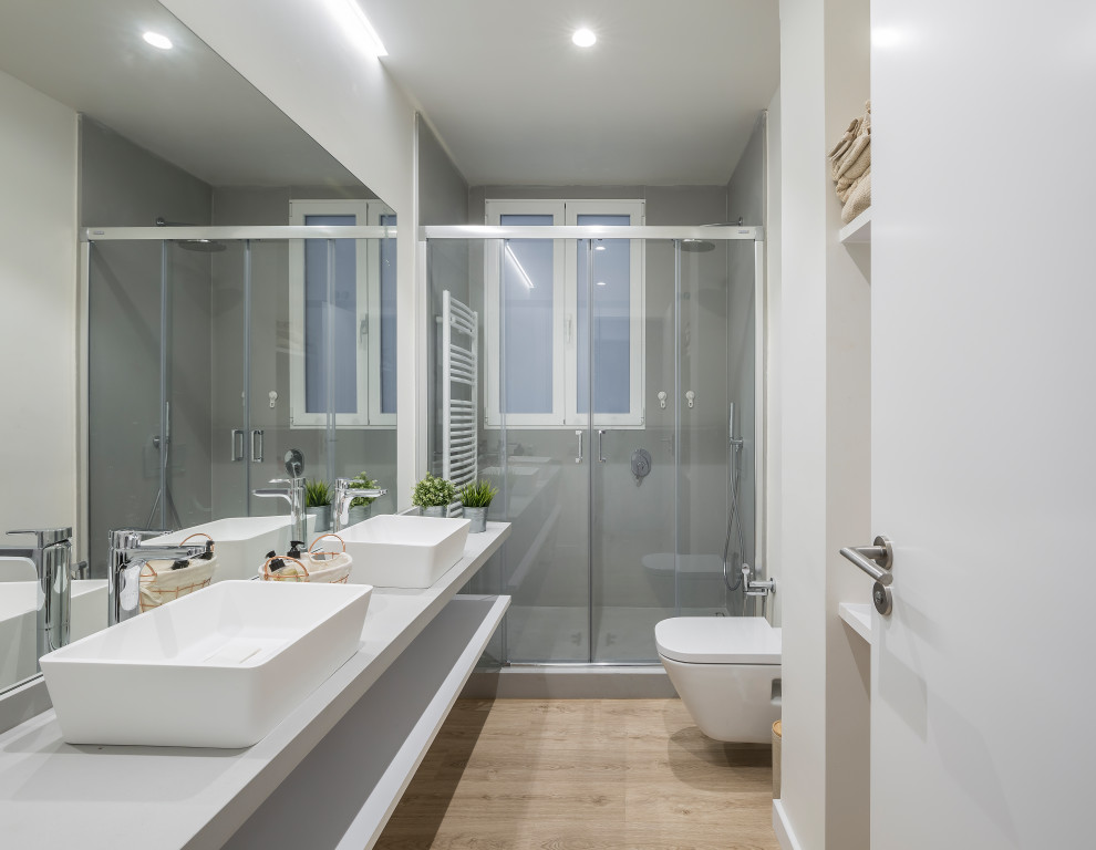 Exempel på ett mellanstort modernt vit vitt badrum med dusch, med vita skåp, en dusch i en alkov, ett urinoar, grå väggar, bänkskiva i kvarts, brunt golv, dusch med gångjärnsdörr, öppna hyllor, grå kakel, porslinskakel och ett fristående handfat