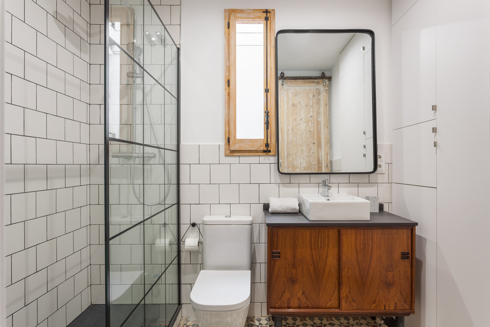 На фото: ванная комната среднего размера в средиземноморском стиле с открытыми фасадами, душем без бортиков, белой плиткой, душевой кабиной, консольной раковиной и черной столешницей с