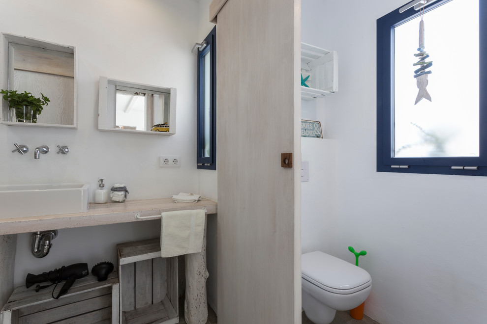 Diseño de cuarto de baño rústico de tamaño medio con armarios abiertos, puertas de armario de madera clara, ducha empotrada, sanitario de una pieza, paredes blancas, aseo y ducha, lavabo sobreencimera y encimera de madera