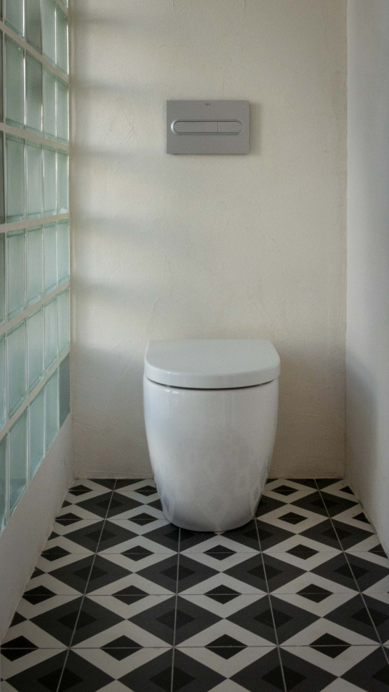 Idée de décoration pour une salle de bain principale méditerranéenne en bois brun de taille moyenne avec un placard en trompe-l'oeil, une douche ouverte, WC à poser, un carrelage noir et blanc, des carreaux de céramique, un mur gris, une vasque, un plan de toilette en bois et une cabine de douche avec un rideau.