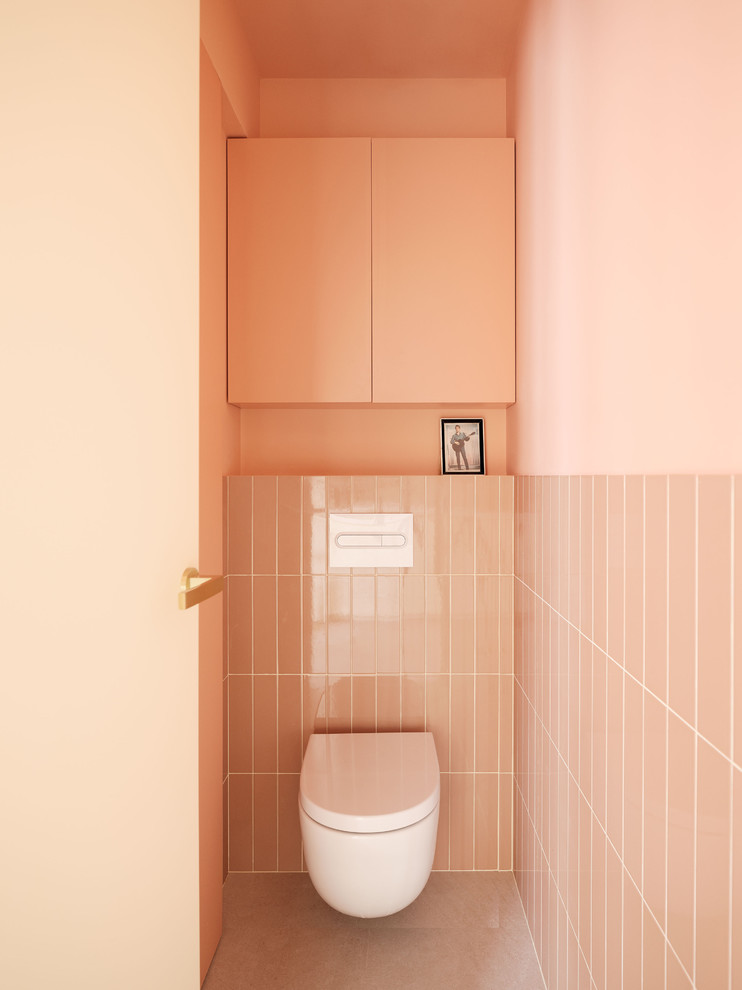 Пример оригинального дизайна: туалет в современном стиле с инсталляцией, розовой плиткой, розовыми стенами и серым полом