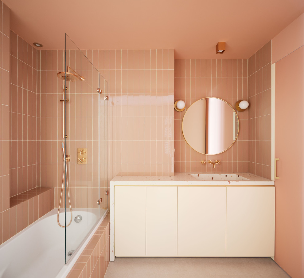 Immagine di una stanza da bagno con doccia minimal con ante lisce, vasca da incasso, vasca/doccia, piastrelle rosa, pareti rosa, lavabo integrato, pavimento grigio, doccia aperta e top bianco