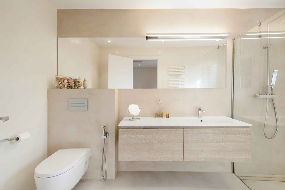 Inspiration för ett mellanstort nordiskt vit vitt badrum med dusch, med släta luckor, skåp i ljust trä, en kantlös dusch, en vägghängd toalettstol, grå väggar, betonggolv, ett integrerad handfat och grått golv