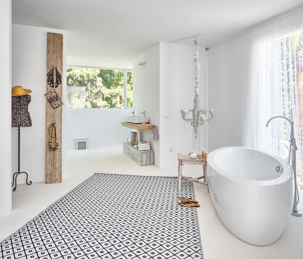 Modelo de cuarto de baño principal y rectangular mediterráneo grande con bañera exenta, paredes blancas, lavabo sobreencimera, encimera de madera y combinación de ducha y bañera