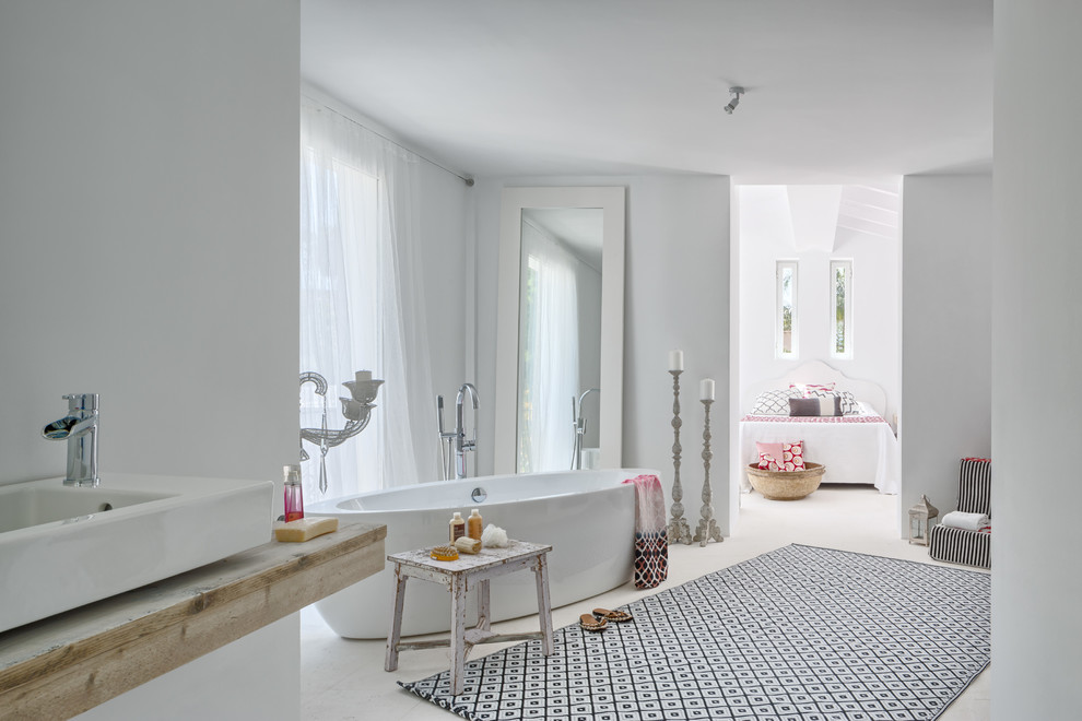 Imagen de cuarto de baño mediterráneo grande con bañera exenta, paredes blancas, lavabo sobreencimera, encimera de madera y combinación de ducha y bañera
