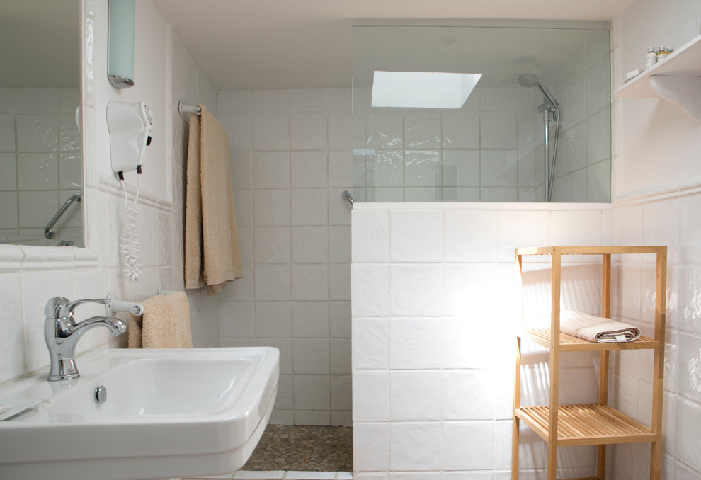 Modelo de cuarto de baño mediterráneo de tamaño medio con ducha abierta, paredes blancas, aseo y ducha y lavabo con pedestal