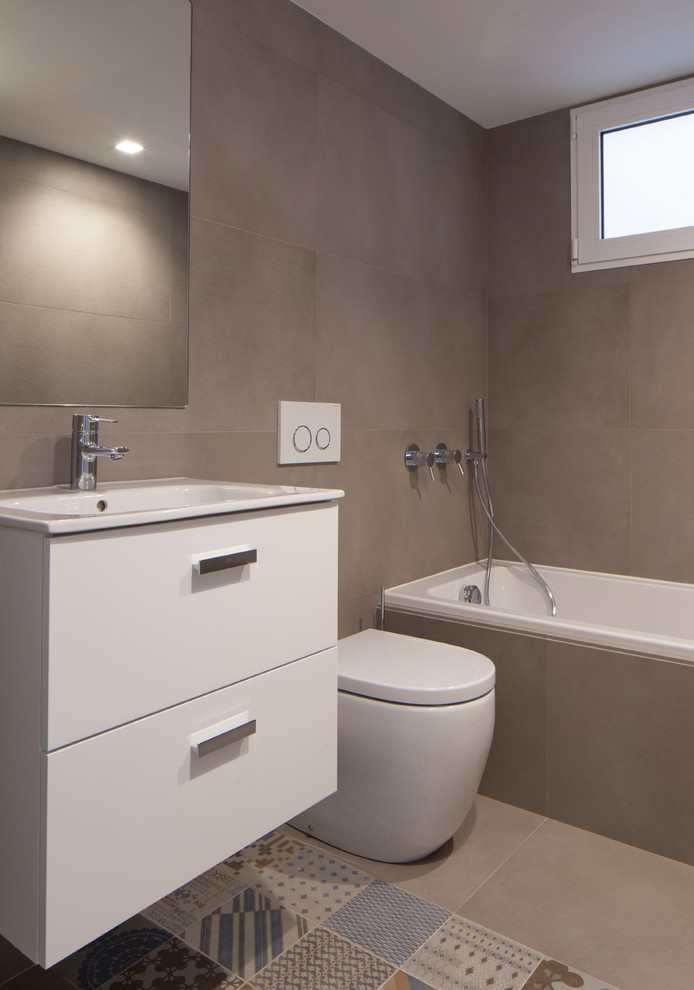 Пример оригинального дизайна: ванная комната среднего размера в скандинавском стиле с фасадами островного типа, белыми фасадами, ванной в нише, унитазом-моноблоком, бежевой плиткой, керамической плиткой, бежевыми стенами, полом из керамической плитки и накладной раковиной