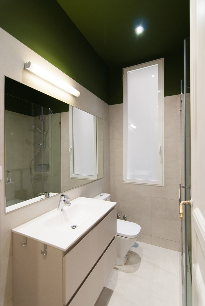 Inredning av ett modernt litet badrum med dusch, med gröna väggar, klinkergolv i keramik, beiget golv, möbel-liknande, beige skåp, våtrum, en toalettstol med separat cisternkåpa, beige kakel, keramikplattor, ett avlångt handfat, bänkskiva i akrylsten och dusch med gångjärnsdörr
