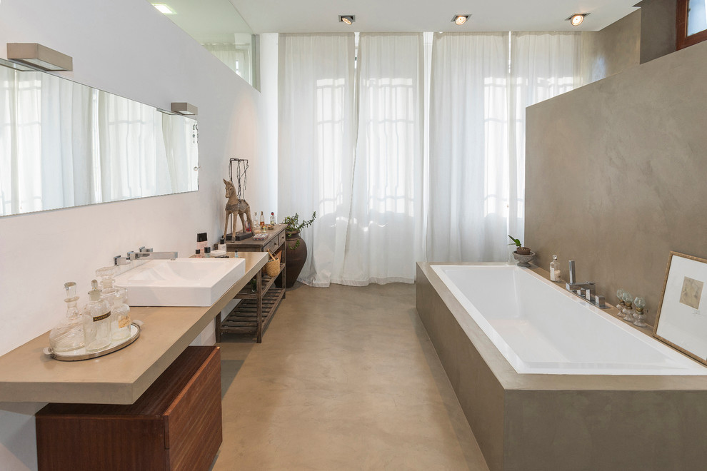 Modern inredning av ett stort en-suite badrum, med öppna hyllor, ett platsbyggt badkar, en kantlös dusch, en toalettstol med hel cisternkåpa, vita väggar, betonggolv, ett fristående handfat, bänkskiva i betong, grått golv och med dusch som är öppen