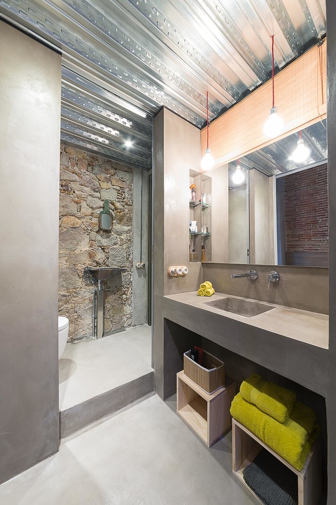 Industriell inredning av ett mellanstort badrum med dusch, med öppna hyllor, en kantlös dusch, betonggolv och ett integrerad handfat