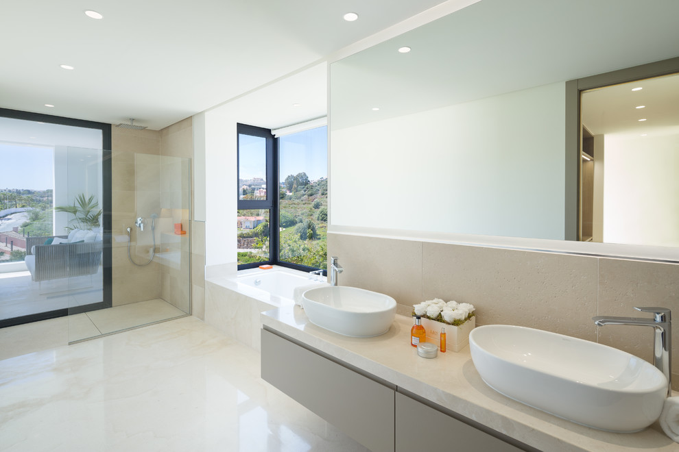 Exempel på ett modernt beige beige en-suite badrum, med släta luckor, en kantlös dusch, beige kakel, beige väggar, ett fristående handfat, beige skåp, ett platsbyggt badkar, beiget golv och med dusch som är öppen
